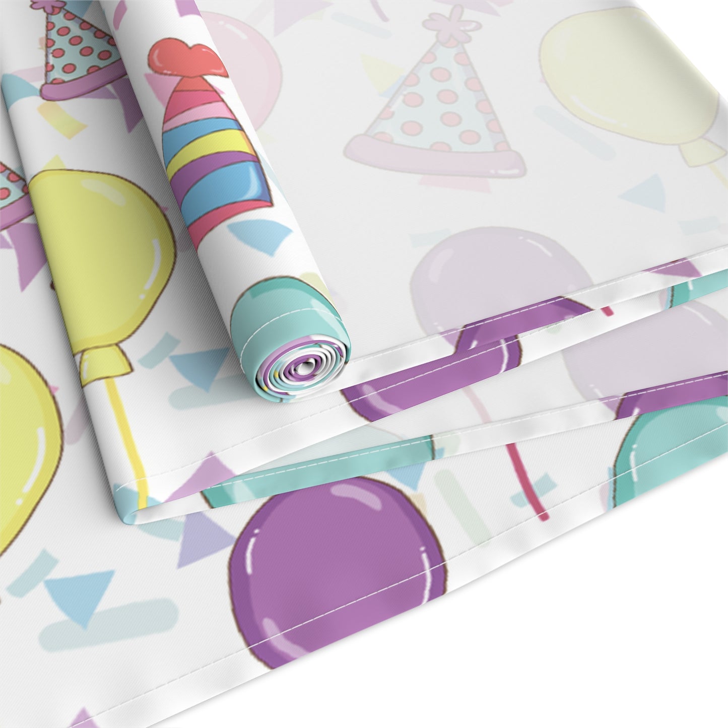 Back view of rolled up table runner with birthday hats, confetti and purple, yellow, blue and pink balloons design on a white background