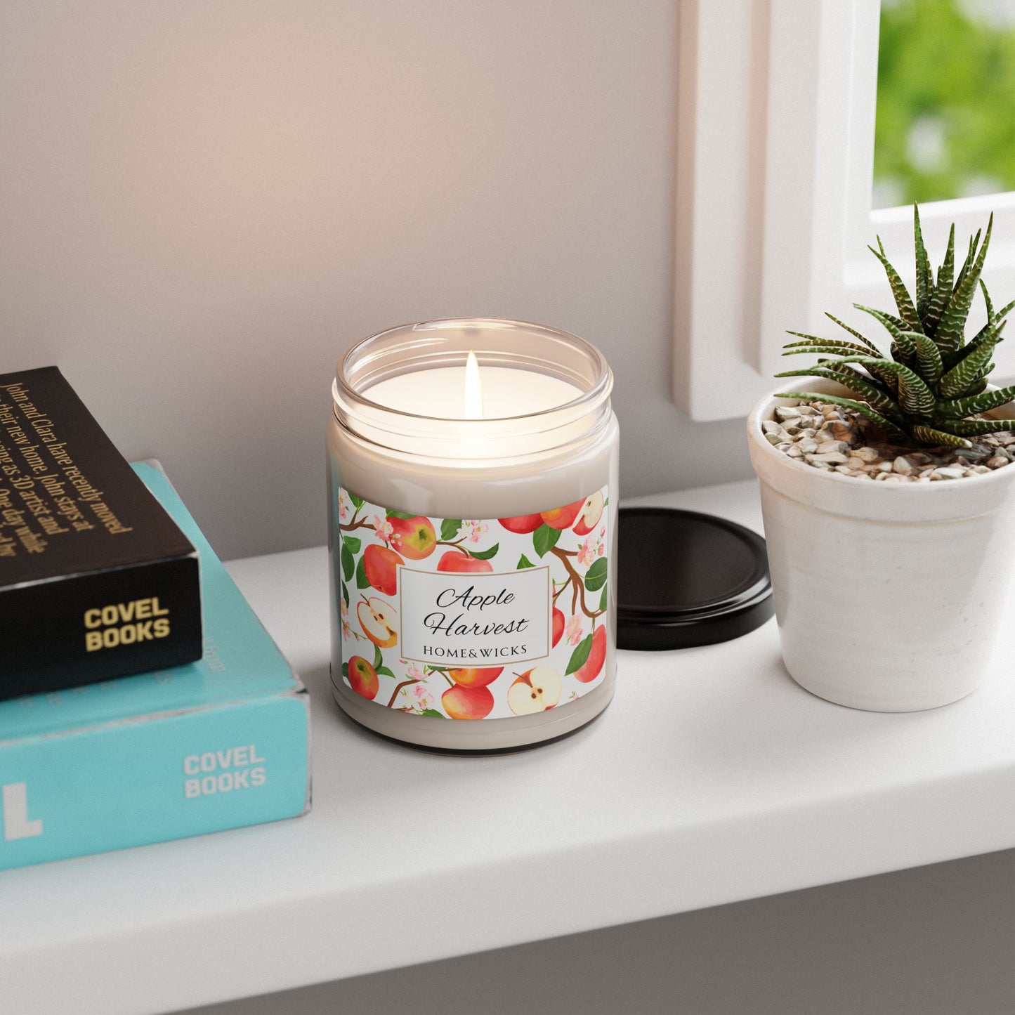 Candle labeled 'Apple Harvest' on a shelf with books and a plant