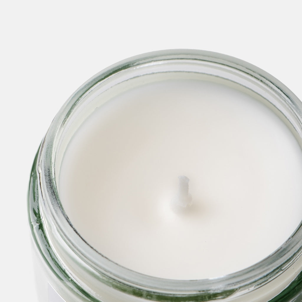 Close-up of cotton wick candle in a glass jar on a white background
