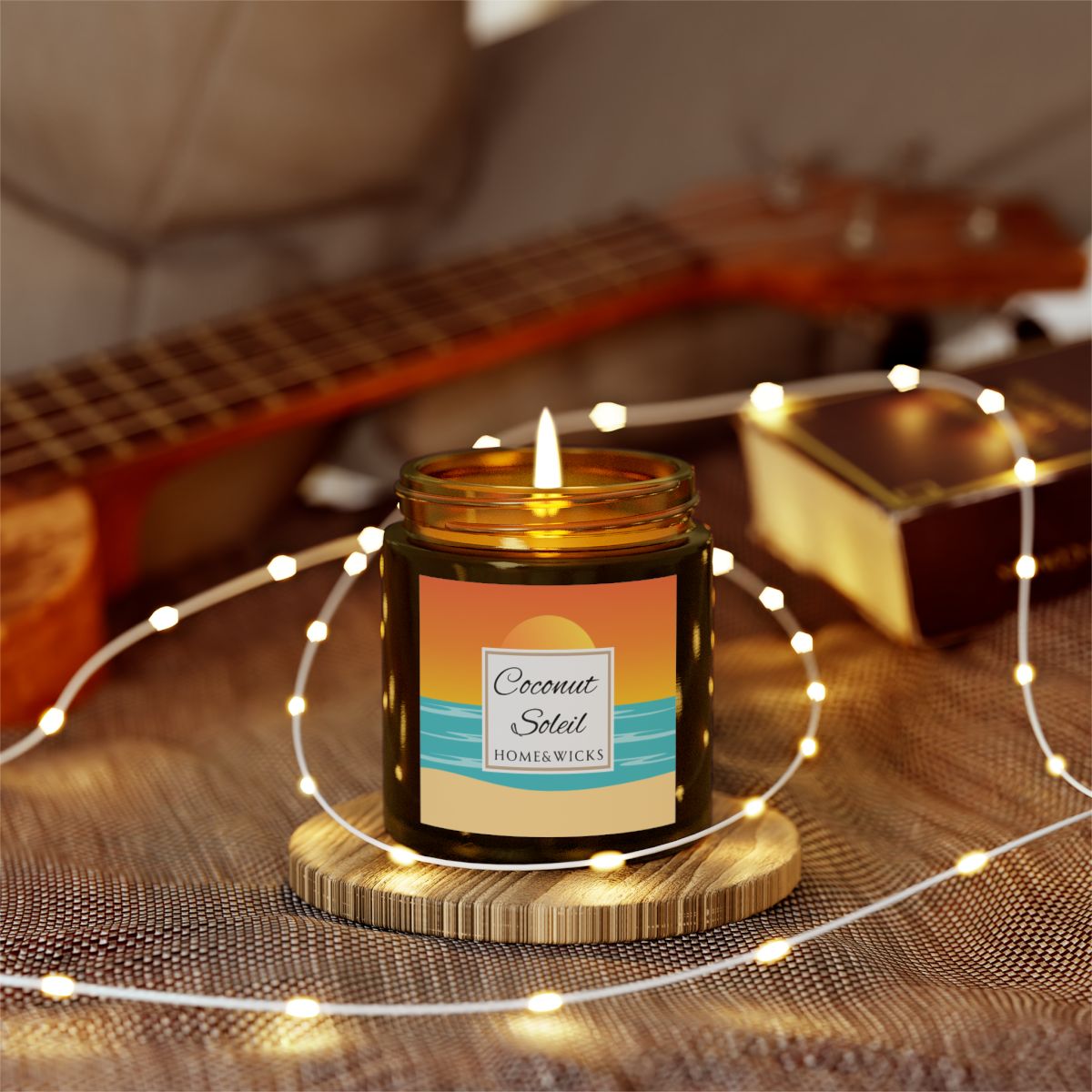 Coconut Soleil candle in 4 oz. amber glass jar with gold lid with a colorful sunset label on a white background by Home & Wicks on a wooden coaster surrounded by string lights, with a guitar in the background.