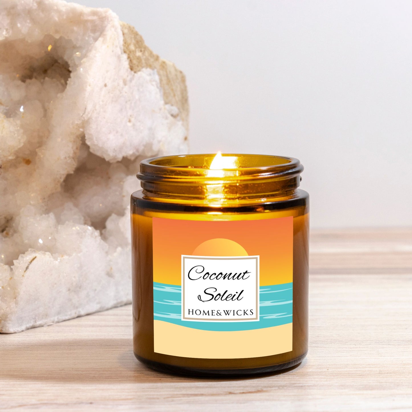 Coconut Soleil candle in 4 oz. amber glass jar with gold lid with a colorful sunset label on a white background by Home & Wicks on a wooden surface with a white background.