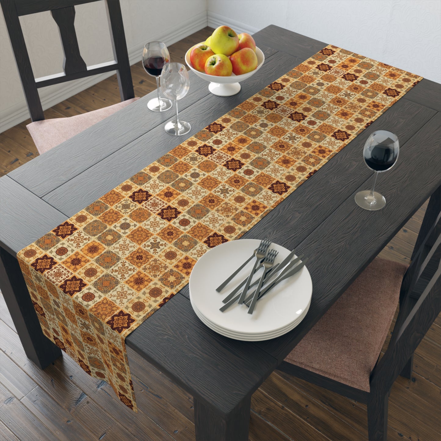 This Fall Flowers Mosaic table runner has a brown, green and gold floral square geometric pattern. This table runner is on a dining table with plates, and glasses.