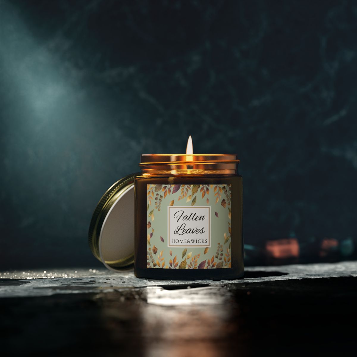 Fallen Leaves candle in a 4 oz. amber glass jar with gold lid with a 'Fallen Leaves' label on a white background by Home & Wicks on a dark background