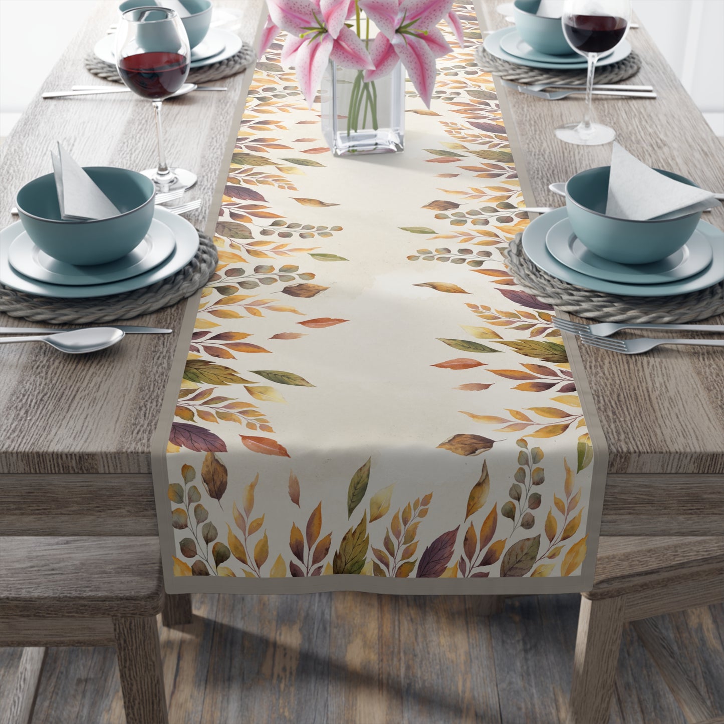 Table setting with a colorful leaf-patterned table runner on a wooden table.