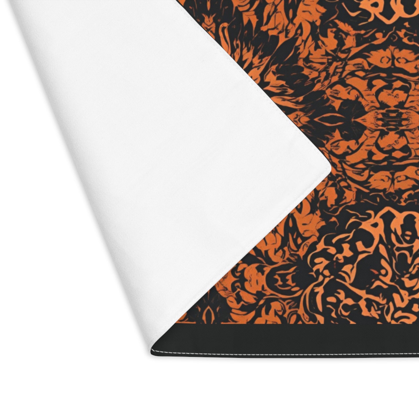 Groovy Black & Orange placemat with intricate black and orange pattern printed on the cotton twill placemat with corner of placemat folded over to reveal white backside.