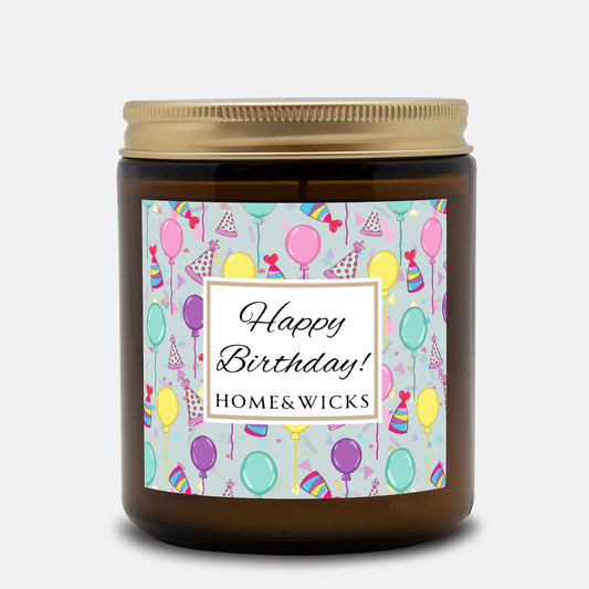 Amber candle jar with gold label with a 'Happy Birthday' label and colorful design with birthday balloons, birthday hats and confetti on a white background