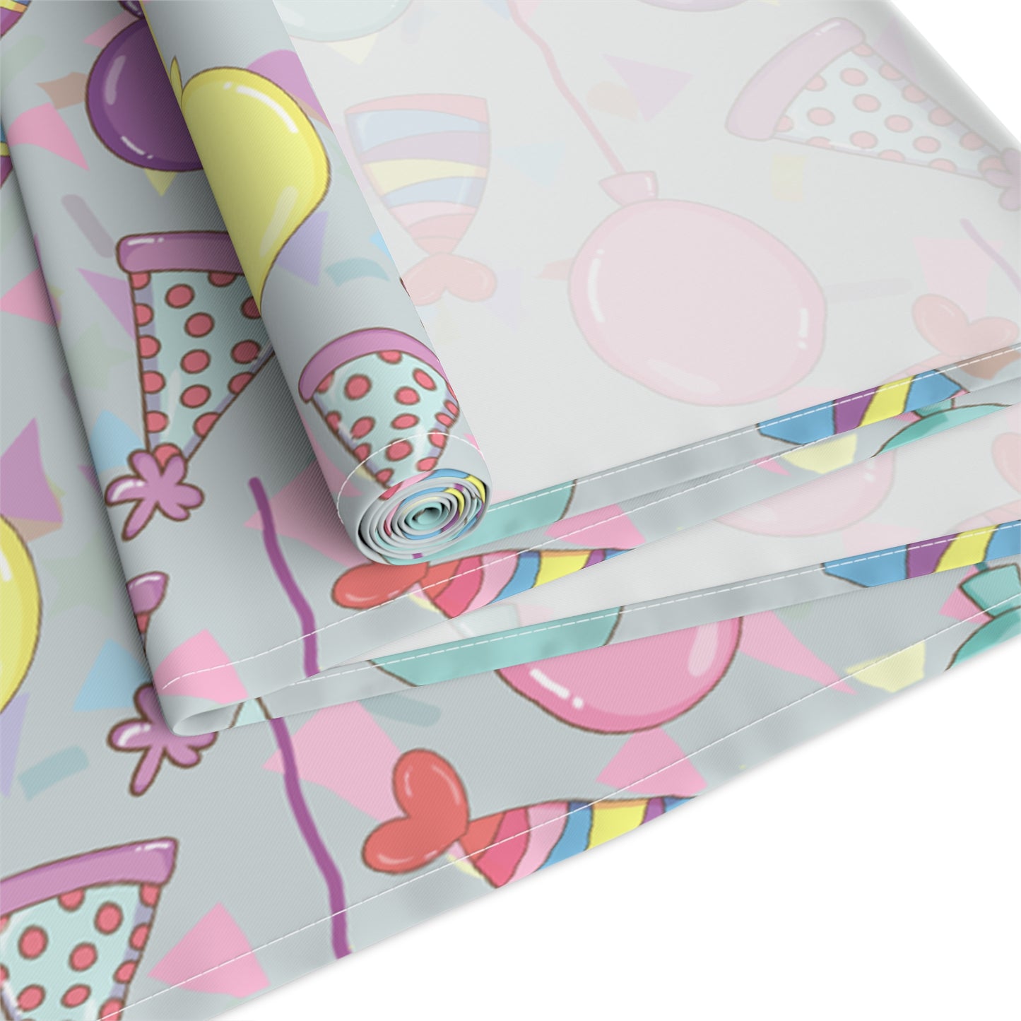 Roll of table runner with colorful birthday party hats, confetti and balloons pattern on a white background.