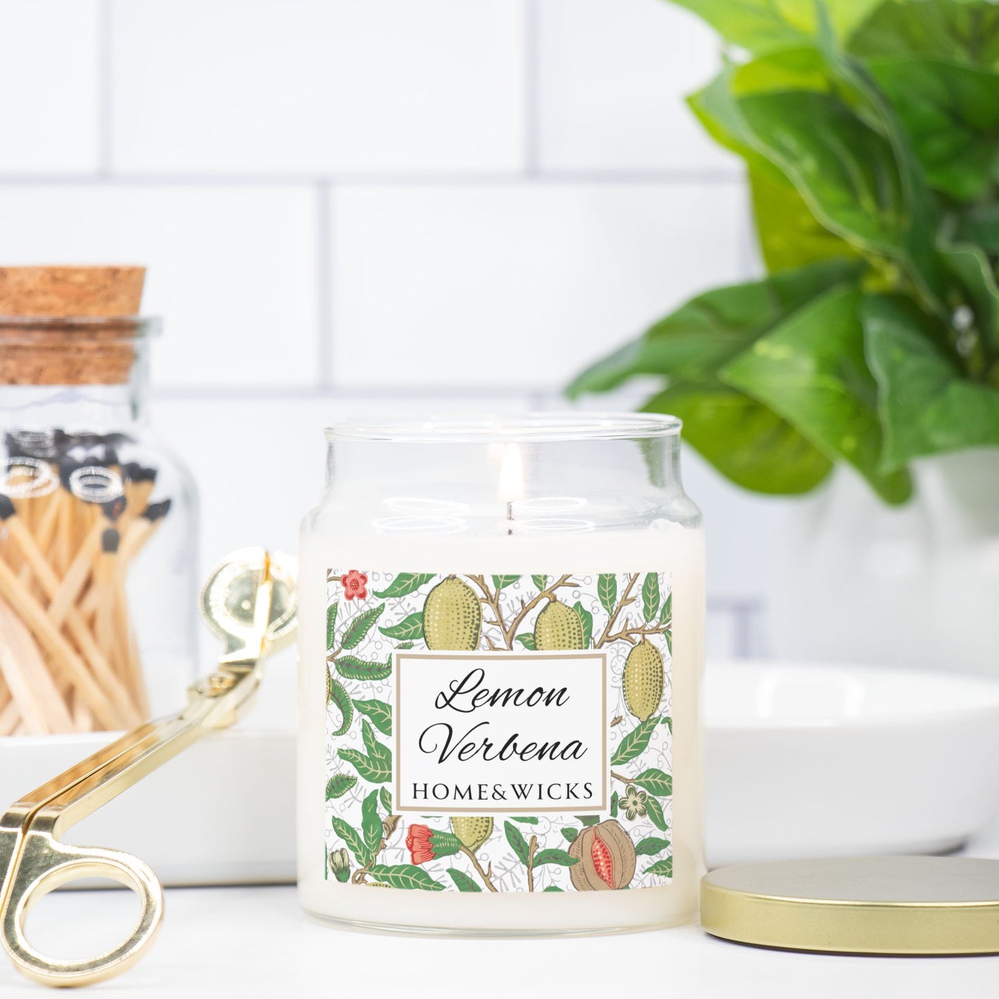 Candle jar labeled 'Lemon Verbena' by HOME&WICKS with decorative elements on a white surface.