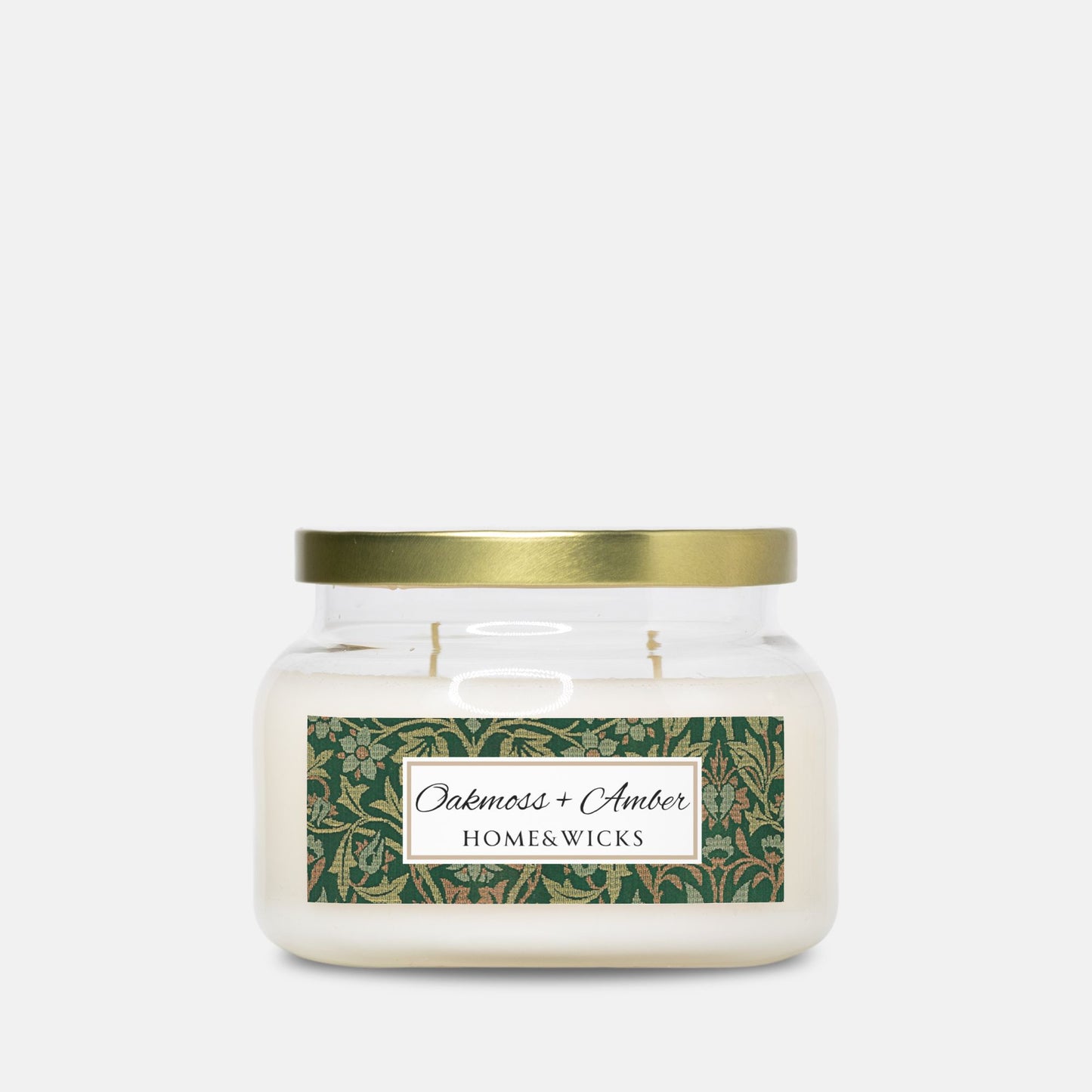 Jar candle with a gold lid and Oakmoss Amber label with Flower Garden by William Morris on a white background