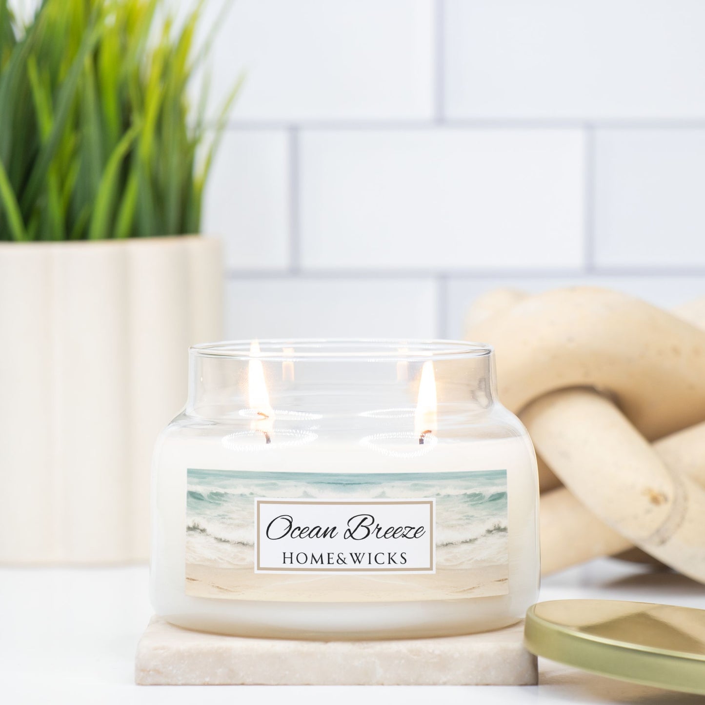 Candle labeled 'Ocean Breeze' from HOME & WICKS on a surface with decorative elements.