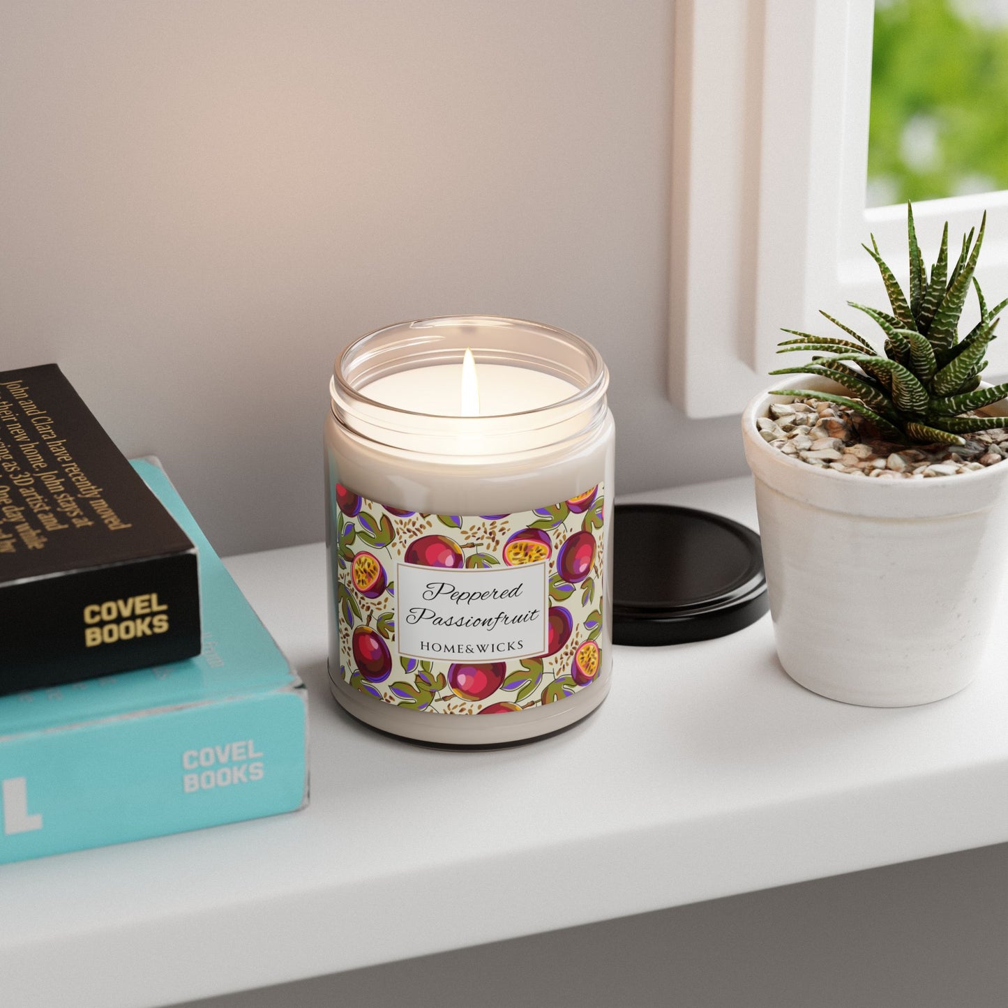 Candle with decorative label on a shelf next to books and a plant