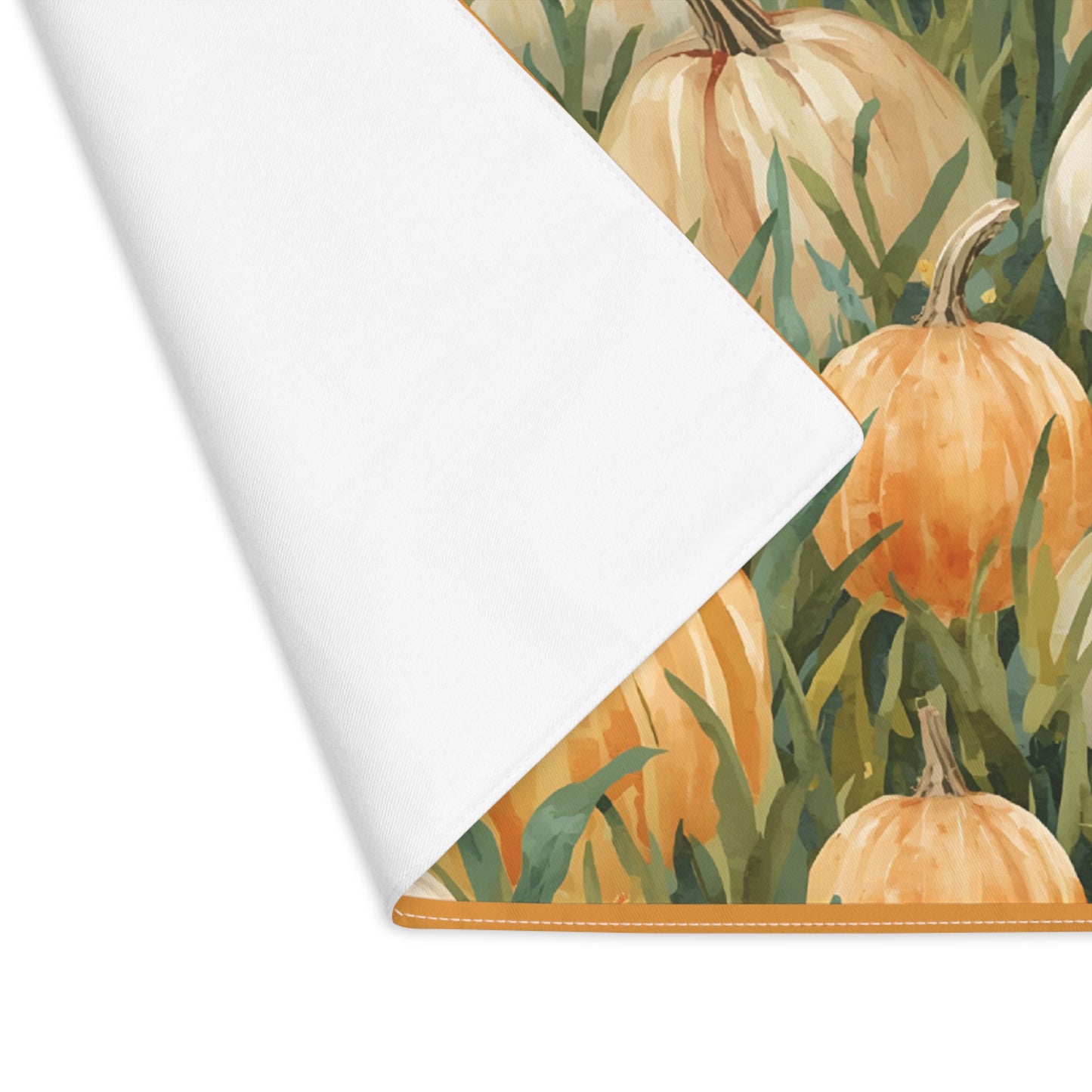 Pumpkin Patch placemat has white and orange pumpkins in grass with orange tulips printed on front of the placemat cotton twill fabric with a corner folded over to reveal white backside and sits on a white background