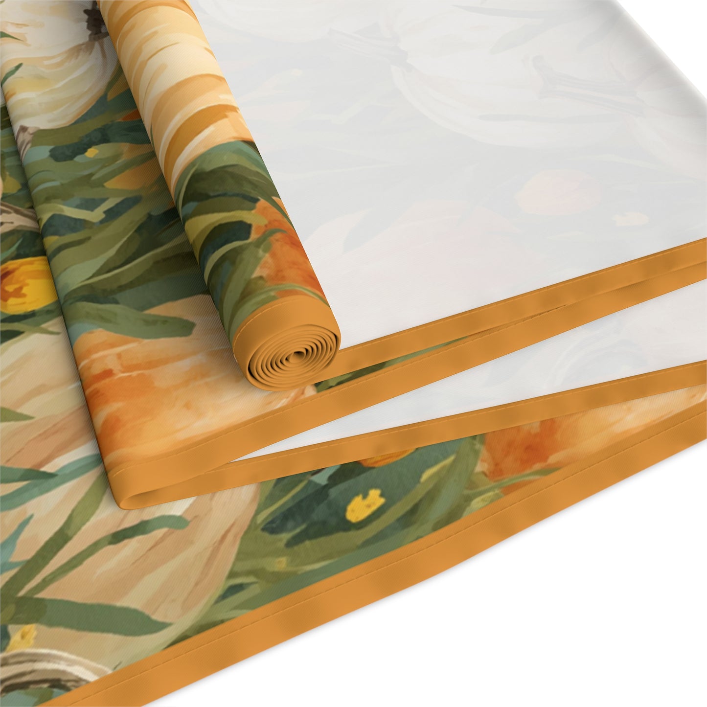 Pumpkin Patch table runner has white and orange pumpkins in grasses printed on front of table runner polyester fabric and is rolled up and folded and sits on a white surface