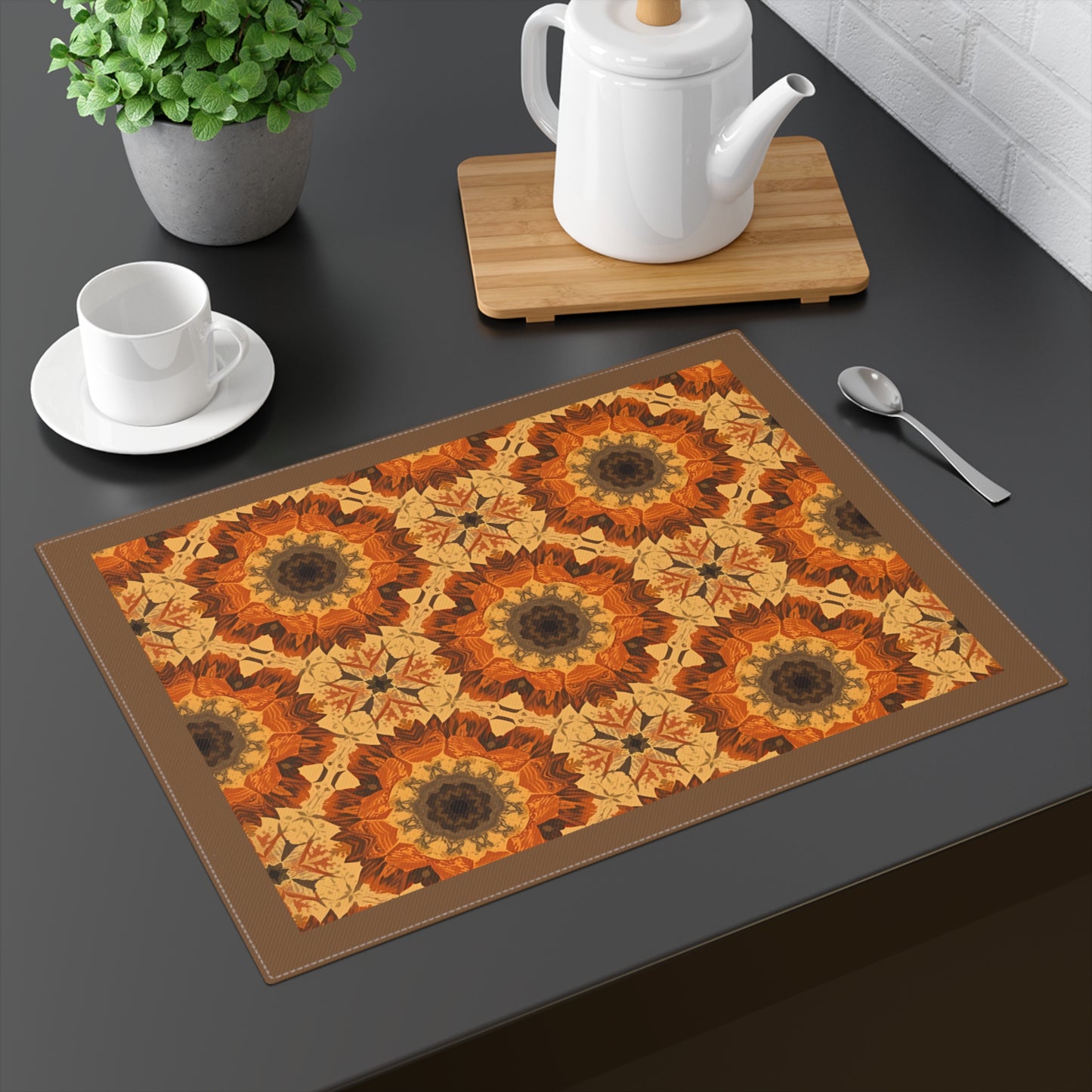 Retro Fall Flowers placemat has orange, yellow and gray geometric tye-dye floral pattern printed on the placemat's cotton twill fabric on a dark table, surrounded by kitchen items.