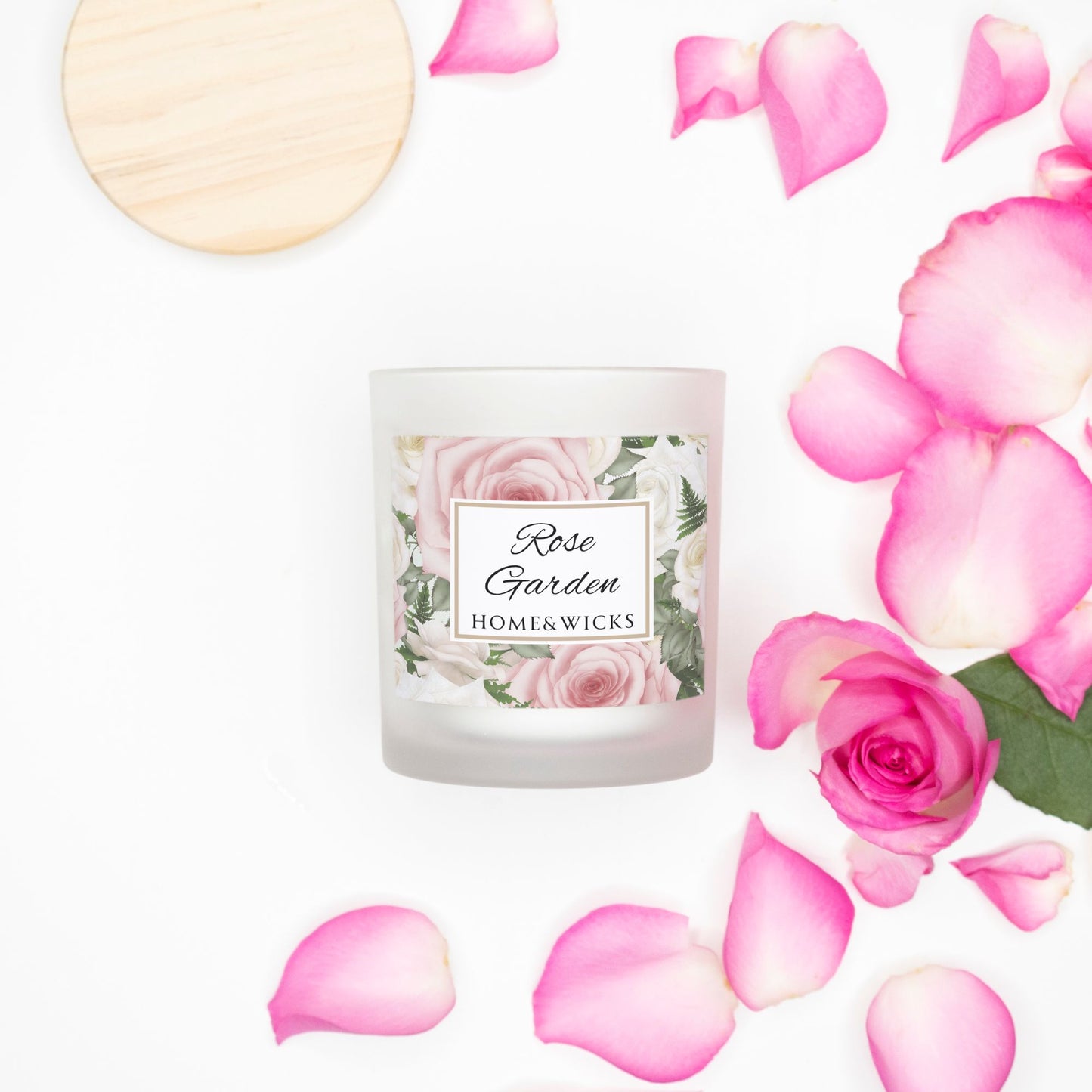 Candle labeled 'Rose Garden' by Homes & Wicks surrounded by pink roses and petals on a white background
