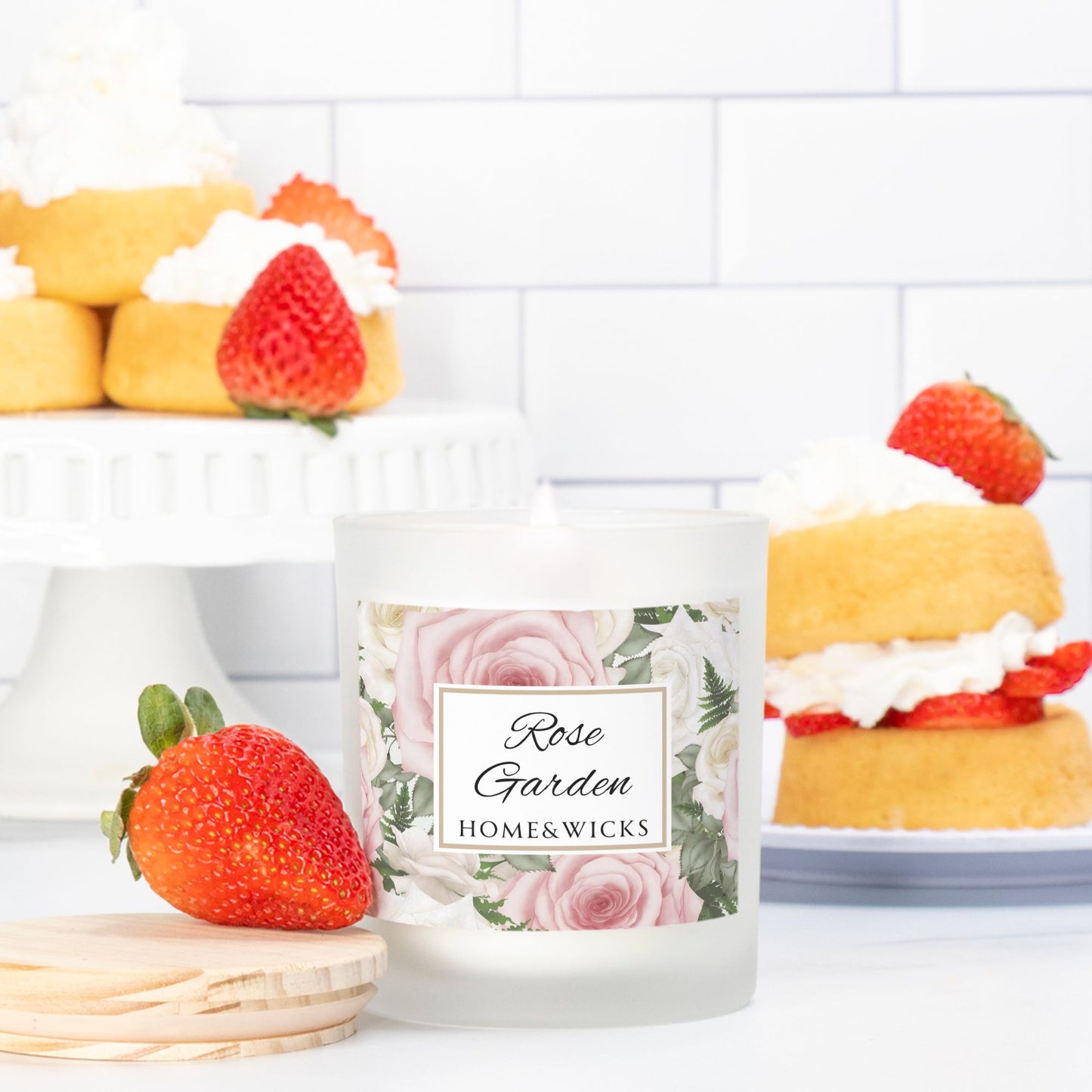 Candle labeled 'Rose Garden' by Home & Wicks with strawberry and cake decorations on a white background