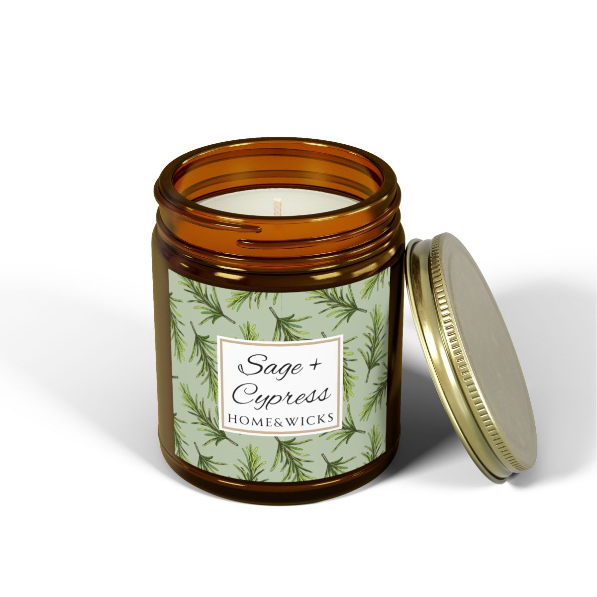 Sage & Cypress candle in an amber jar with gold lid with 'Sage + Cypress' label on a light green background with cypress needle leaves on a white background.