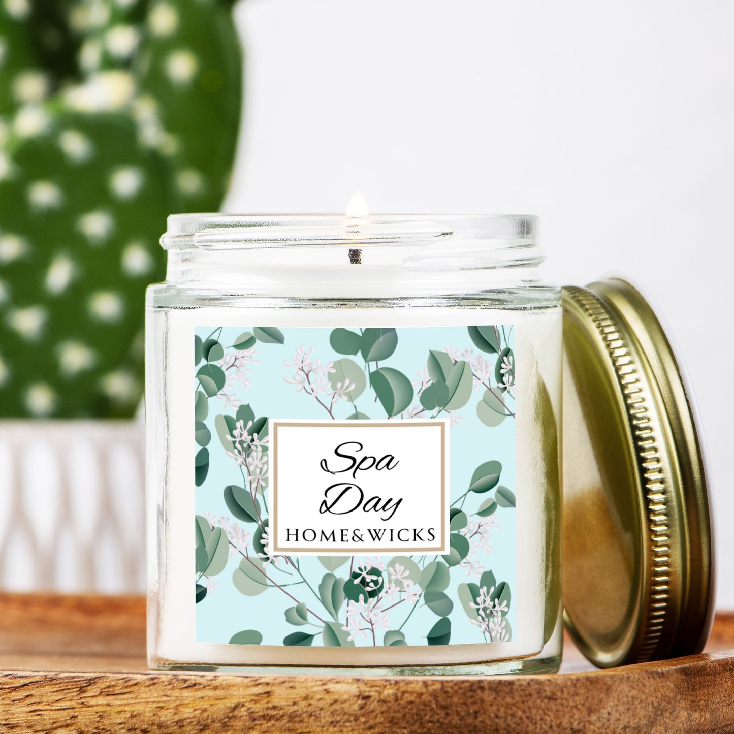 Spa Day candle by Homes & Wicks in a clear candle jar with gold lid with a eucalyptus floral label on a white background on a wooden surface
