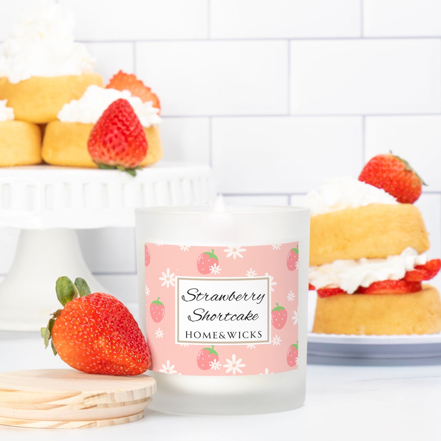 Candle labeled 'Strawberry Shortcake' with pink wood wick and strawberries and shortcakes in the background
