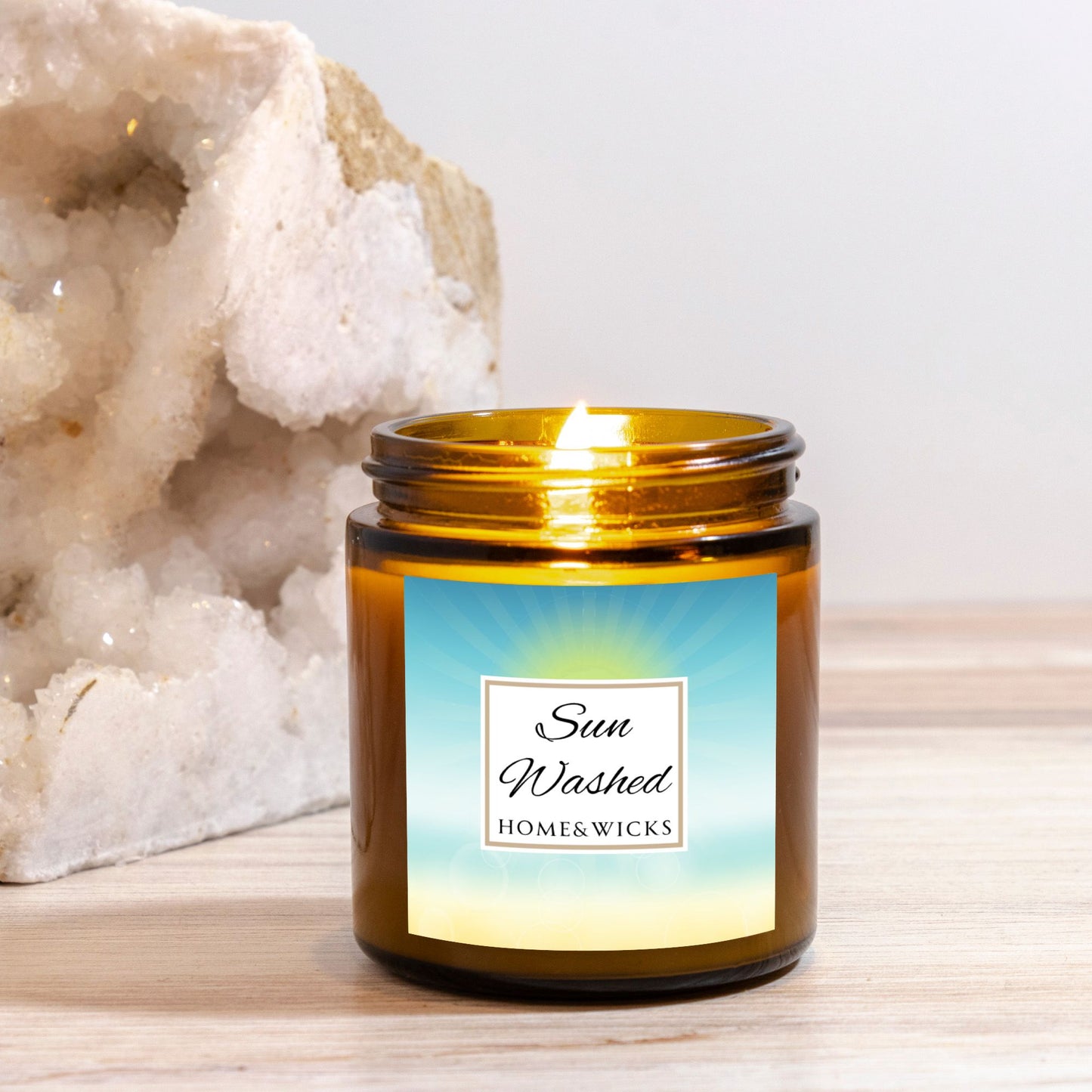 Sun Washed candle in a 4 oz. jar labeled 'Sun Washed' with sun graphic by Home & Wicks on a white background on a light wooden surface.