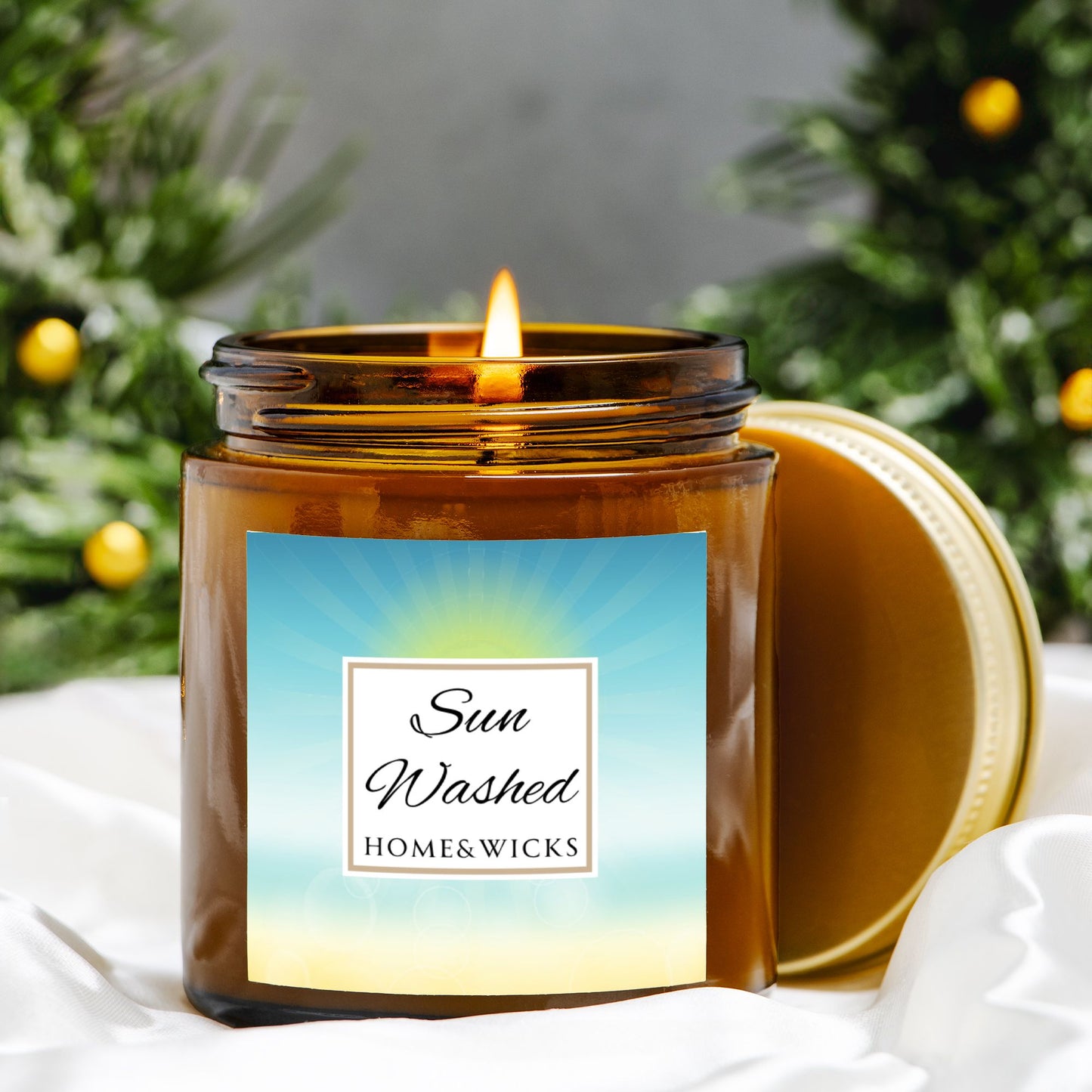 Sun Washed candle in a 4 oz. jar labeled 'Sun Washed' with sun graphic by Home & Wicks on a white background, surrounded by orange tree greenery.