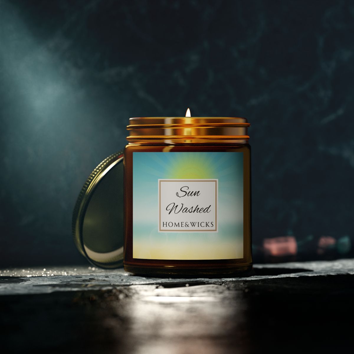 Candle in a 9 oz. amber jar with gold lid with 'Sun Washed' label on with sun graphic gradient background by Home & Wicks on a dark background