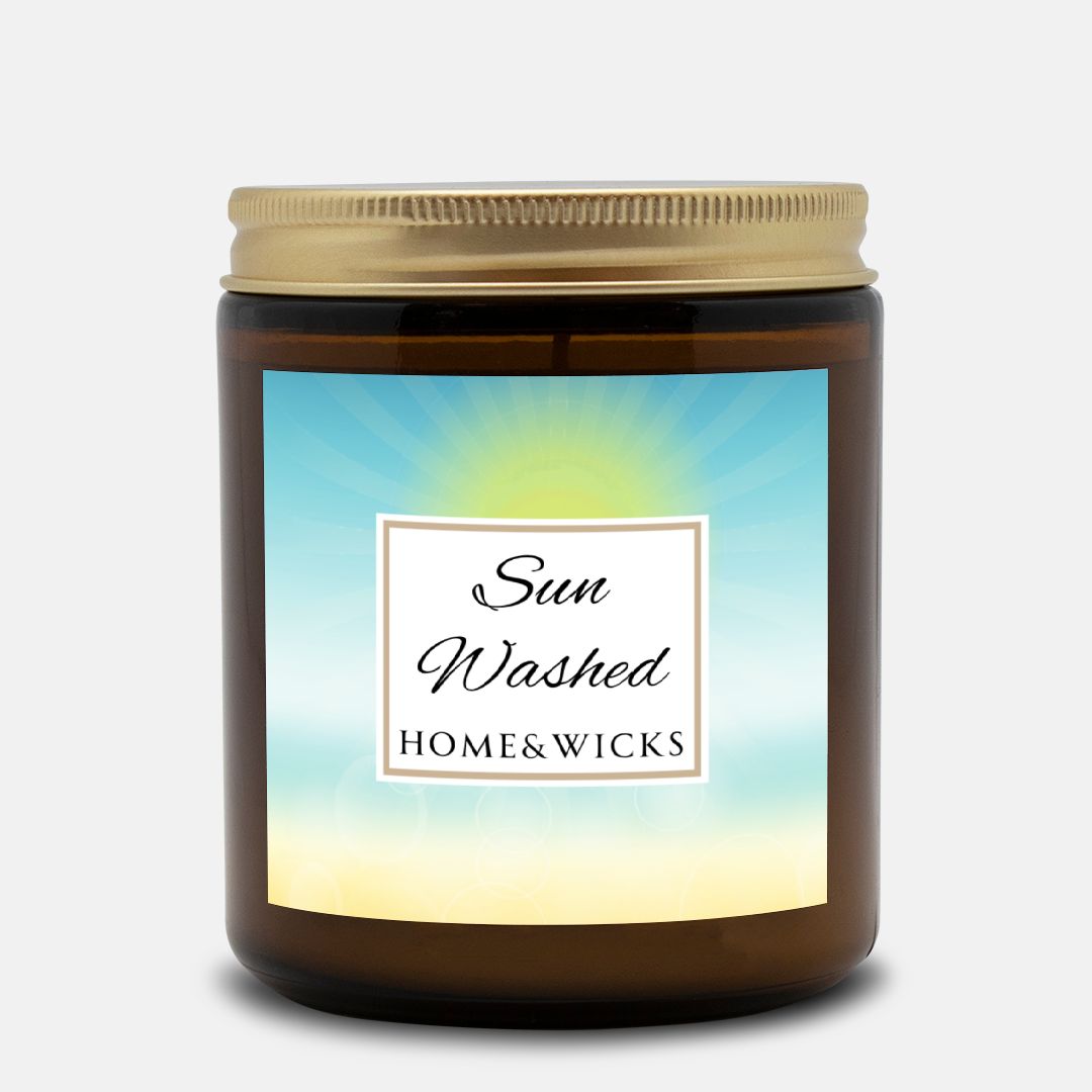 Candle in a 9 oz. amber jar with gold lid with 'Sun Washed' label on with sun graphic gradient background by Home & Wicks