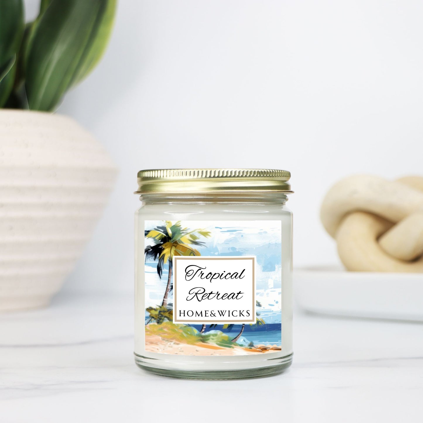 Tropical Retreat clear jar candle with gold lid labeled 'Tropical Retreat' with tropical beach seashore by Home & Wicks on a white background on a light background