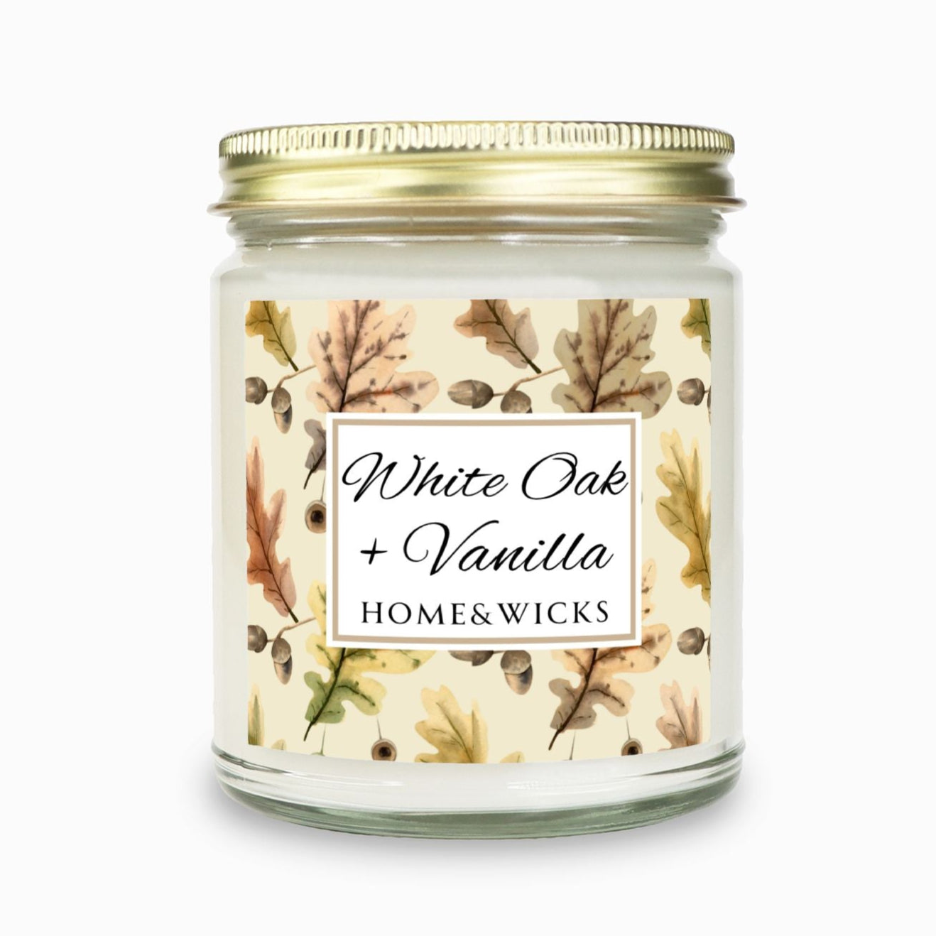 Fall or Thanksgiving candle, "White Oak Vanilla" candle in a clear jar with a gold lid labeled 'White Oak + Vanilla' with oak leaves by Home & Wicks on a white background
