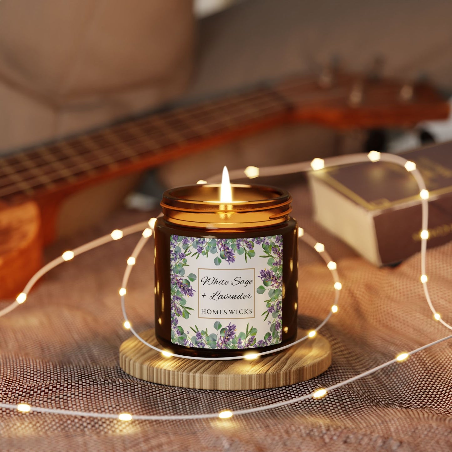 Candle with a floral label on a wooden coaster surrounded by string lights, with a guitar in the background.