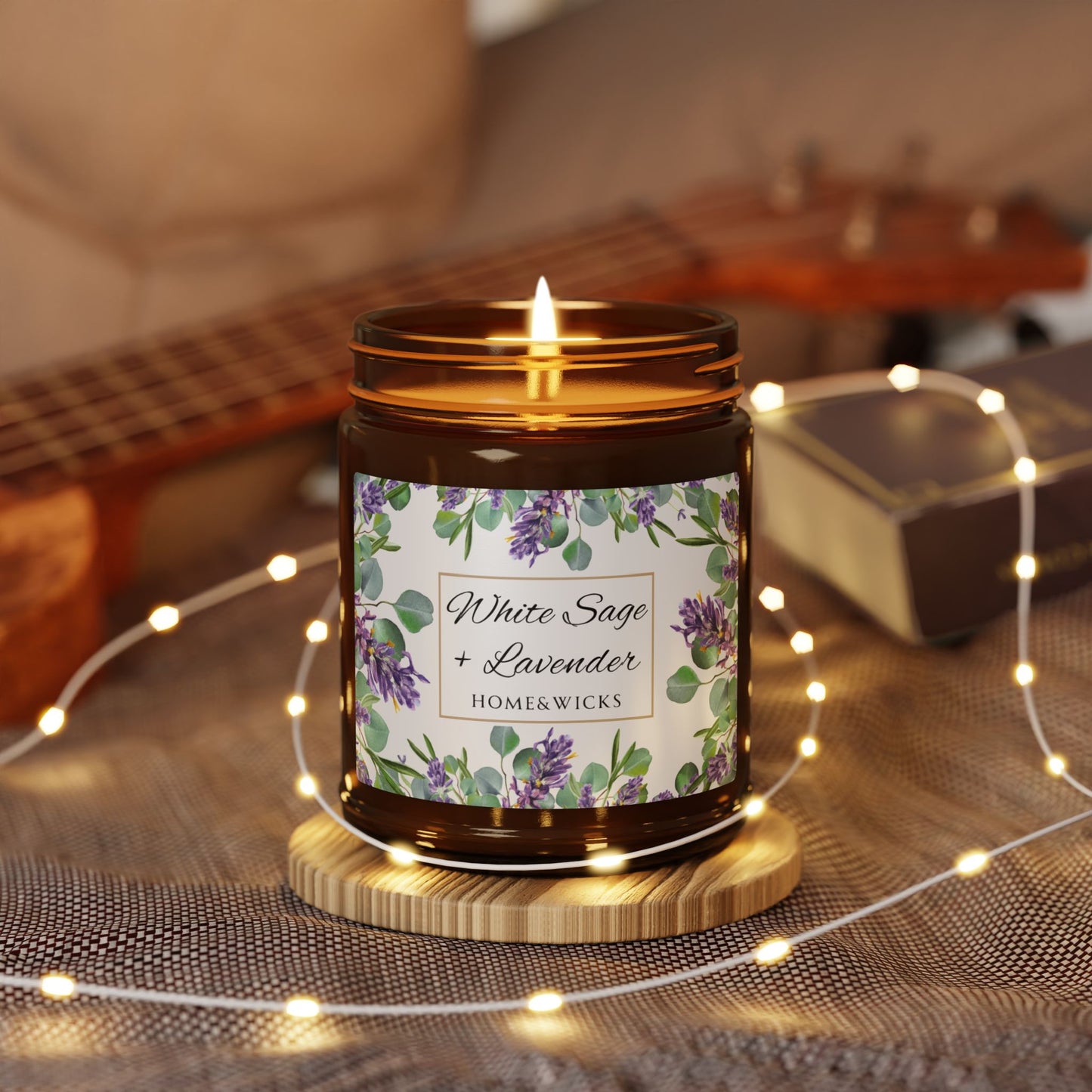 Homewares candle with floral label on a wooden coaster surrounded by string lights and a guitar in the background.