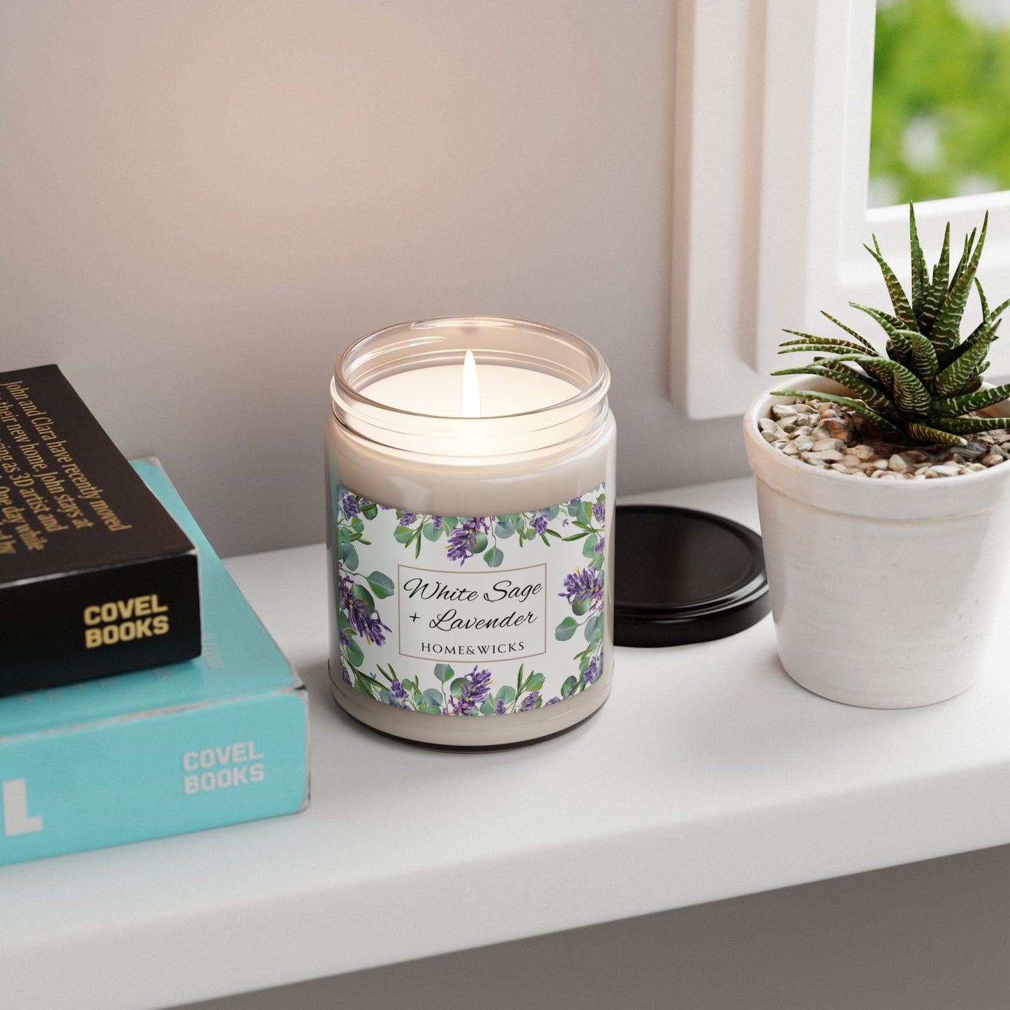 Candle with a floral label on a shelf next to books and a plant