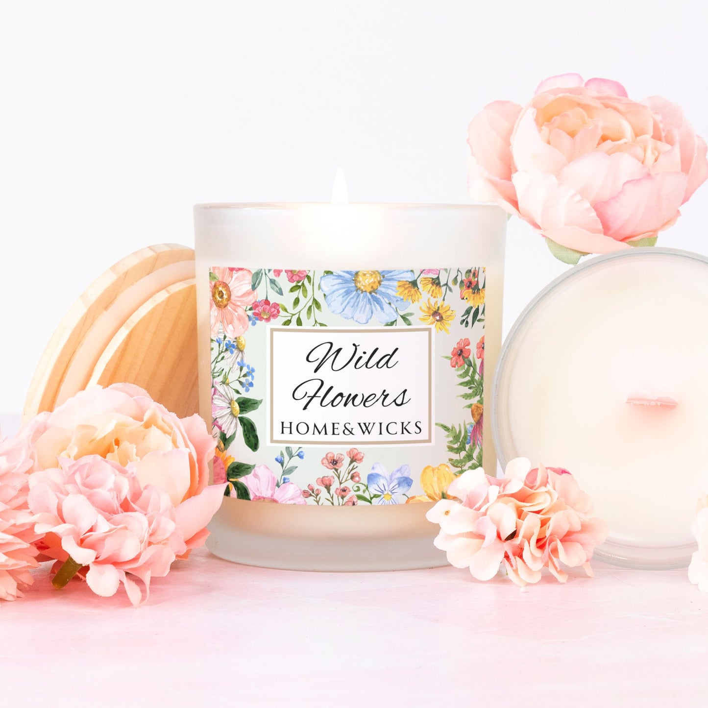 Candle labeled 'Wild Flowers' from Home & Wicks with pink wood wick with floral design on a white background