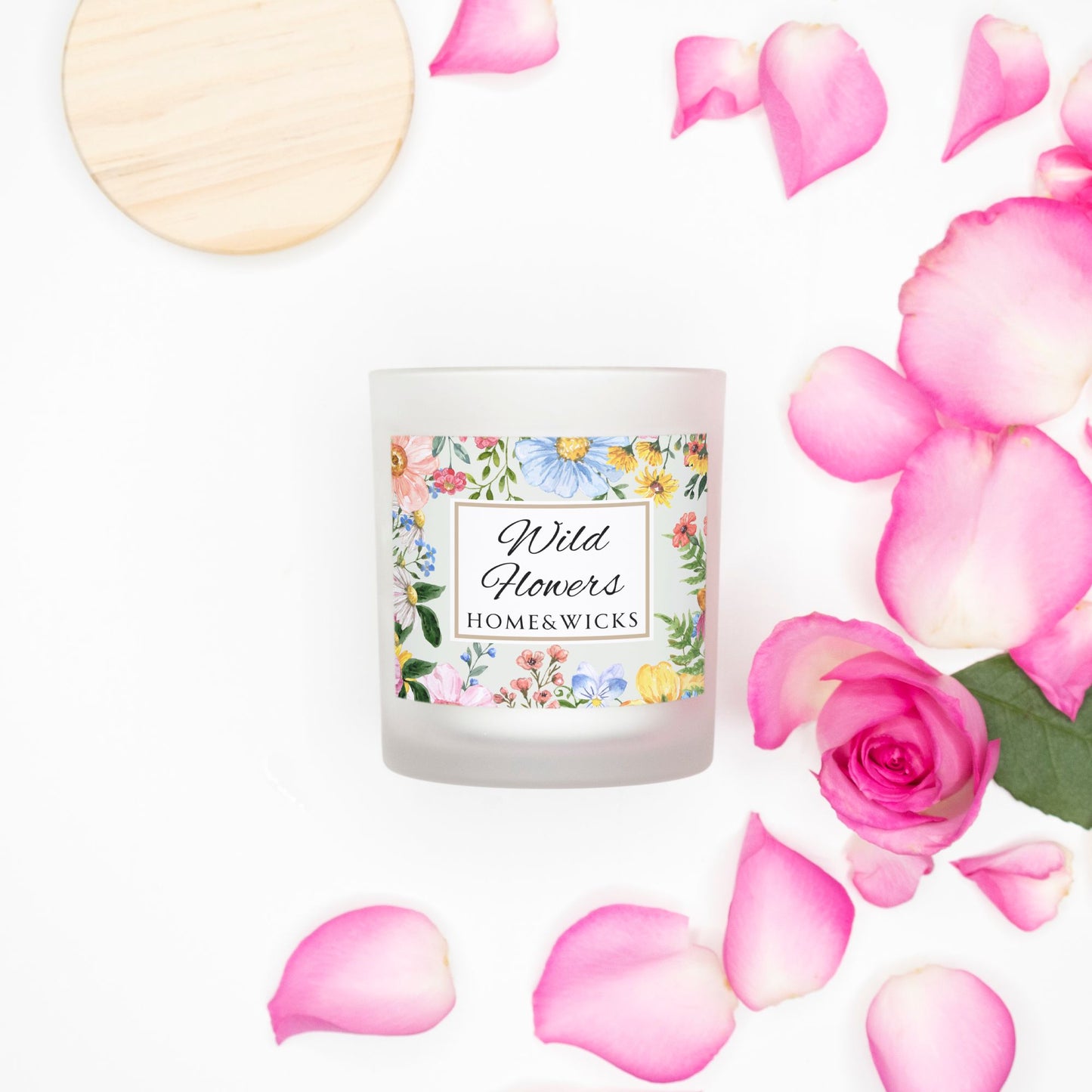 Candle labeled 'Wild Flowers' by Home & Wicks with pink rose petals on a white background