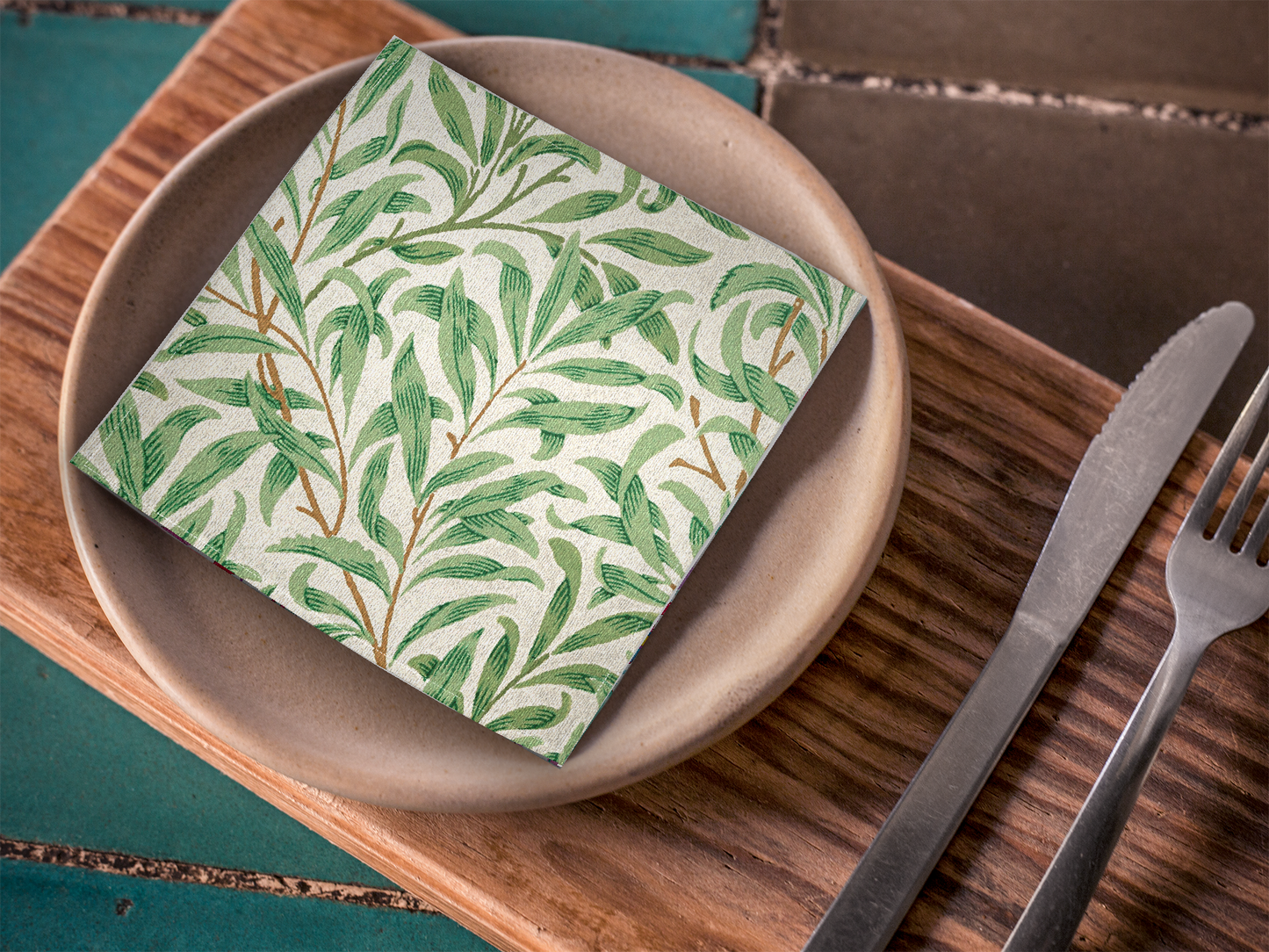 Willow Boughs 10 x 10 cocktail napkin with green leaf willow branch pattern on a wooden plate with cutlery