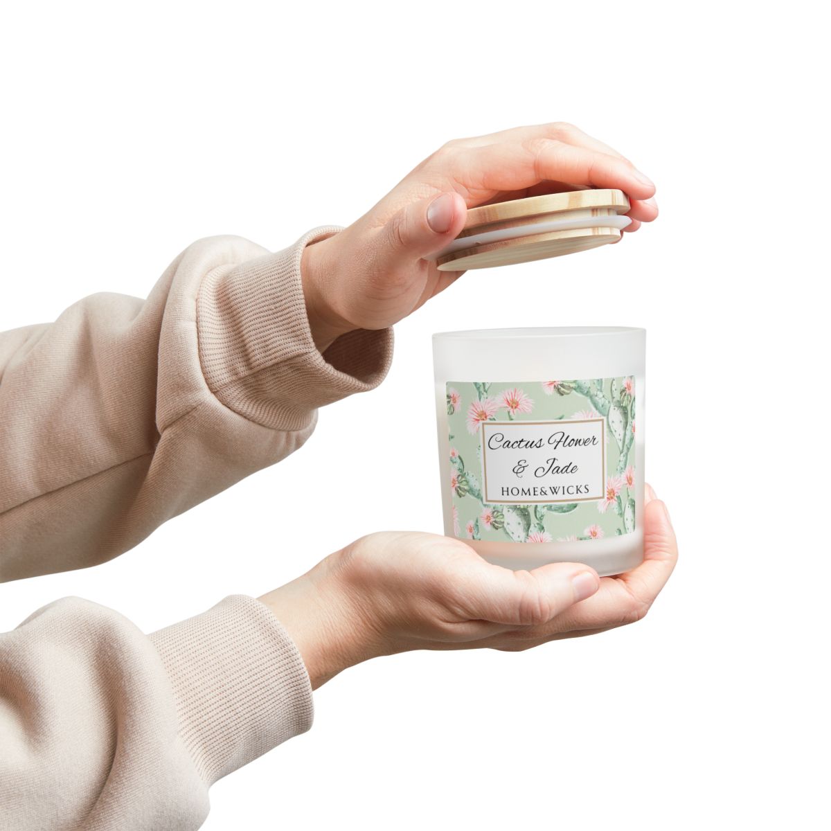 Person holding a candle labeled 'Cactus Flower & Jade' by Home & Wicks on a white background