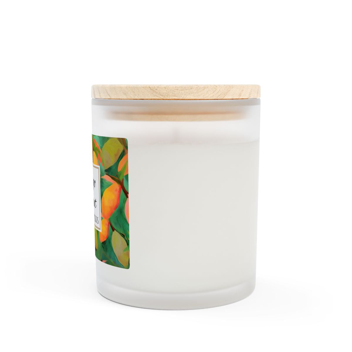 Side view of wood wick candle with a green and orange mango coconut label on a frosted glass candle jar on a white background by Home & Wicks