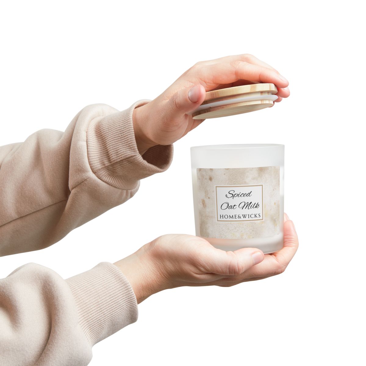 Person holding a candle labeled 'Spiced Oat Milk' by Home & Wicks on a white background