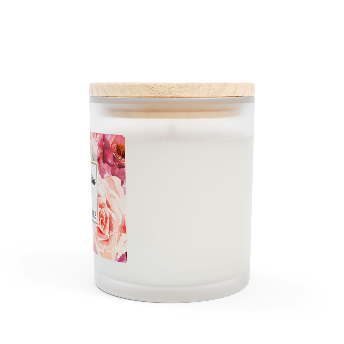 Side view of white frosted candle with a wooden lid and floral label on a white background