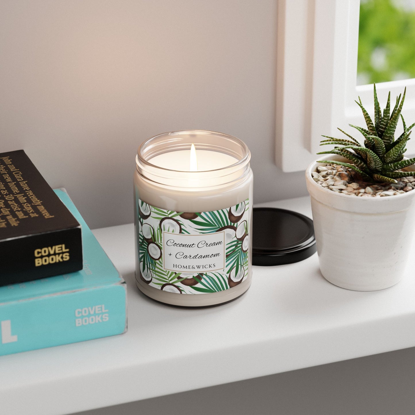 Candle with a decorative coconut cardamom label on a shelf next to books and a plant