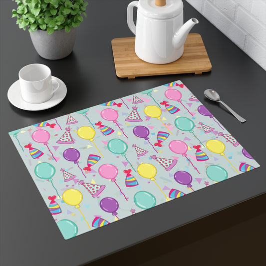 Happy Birthday placemat with with birthday hats, confetti and balloons pattern on a blue-green light cyan background on a dark table 