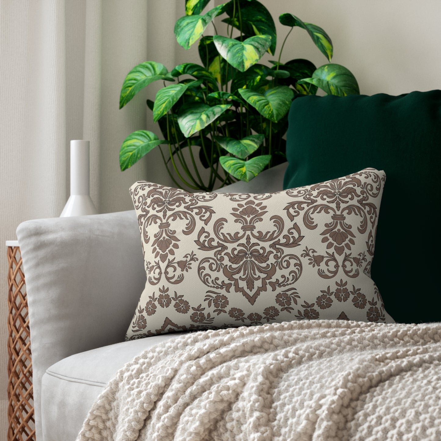 Decorative Baroque Mocha lumbar pillow with floral pattern on a couch with a plant in the background