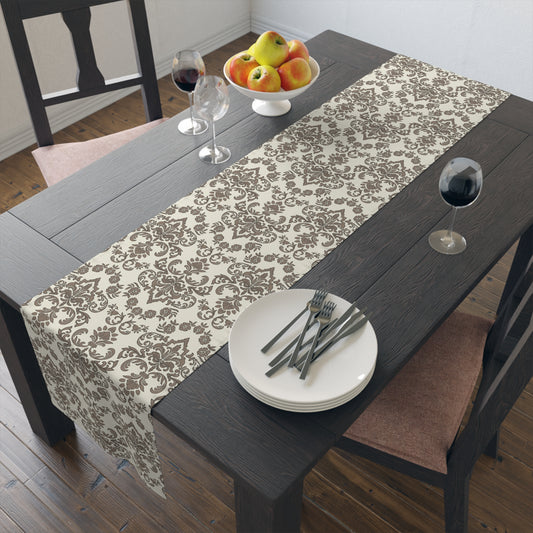 Dining table with a Baroque Mocha table runner, the damask patterned table runner sits on a wood table, along with plates, cutlery, and fruit bowl.