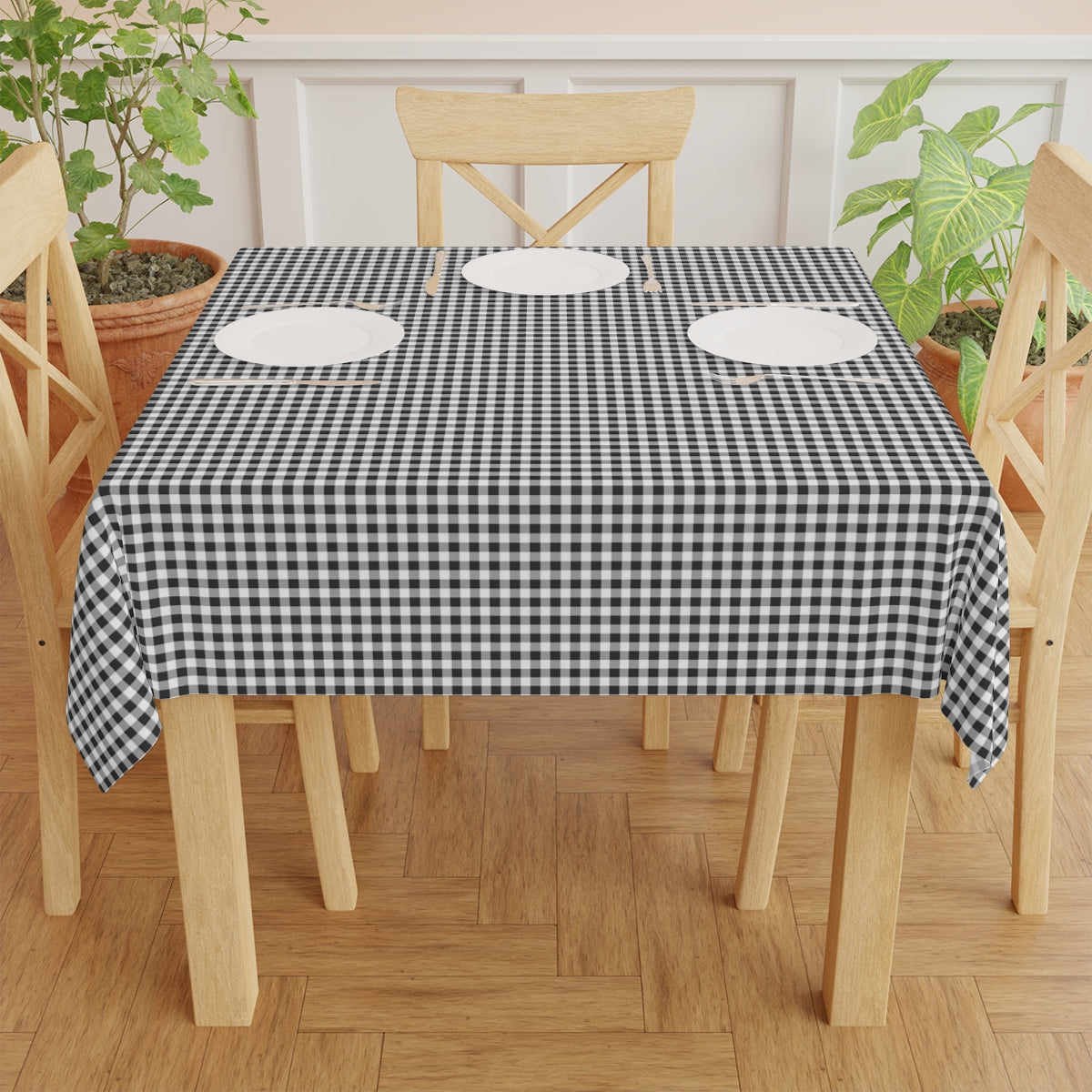 Dining table with a black and white checkered gingham tablecloth, surrounded by wooden chairs, on a wooden floor.