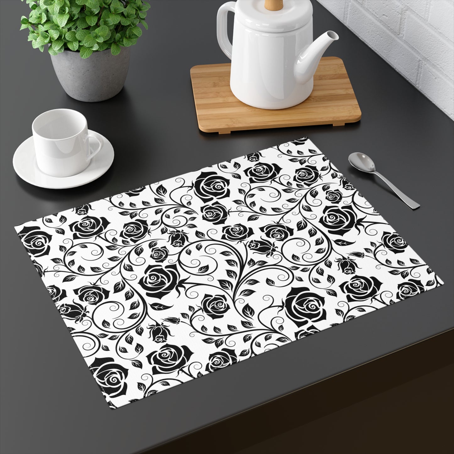 Placemat with black rose pattern on a dark surface with tea set.
