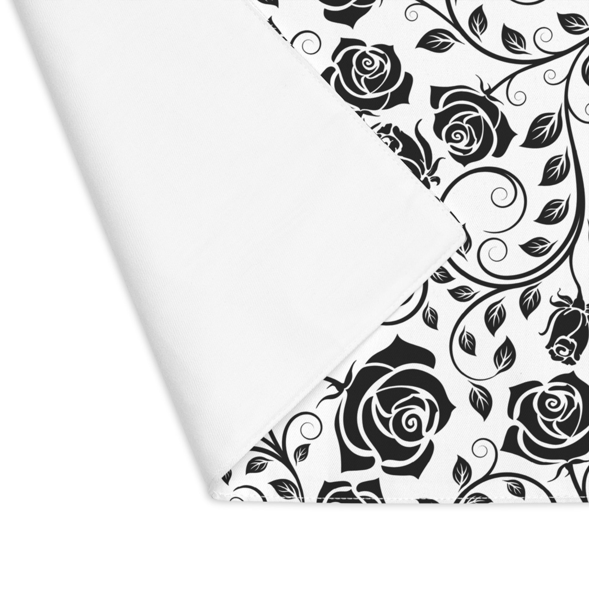 Black and white rose pattern placemat with corner folded over to reveal white background