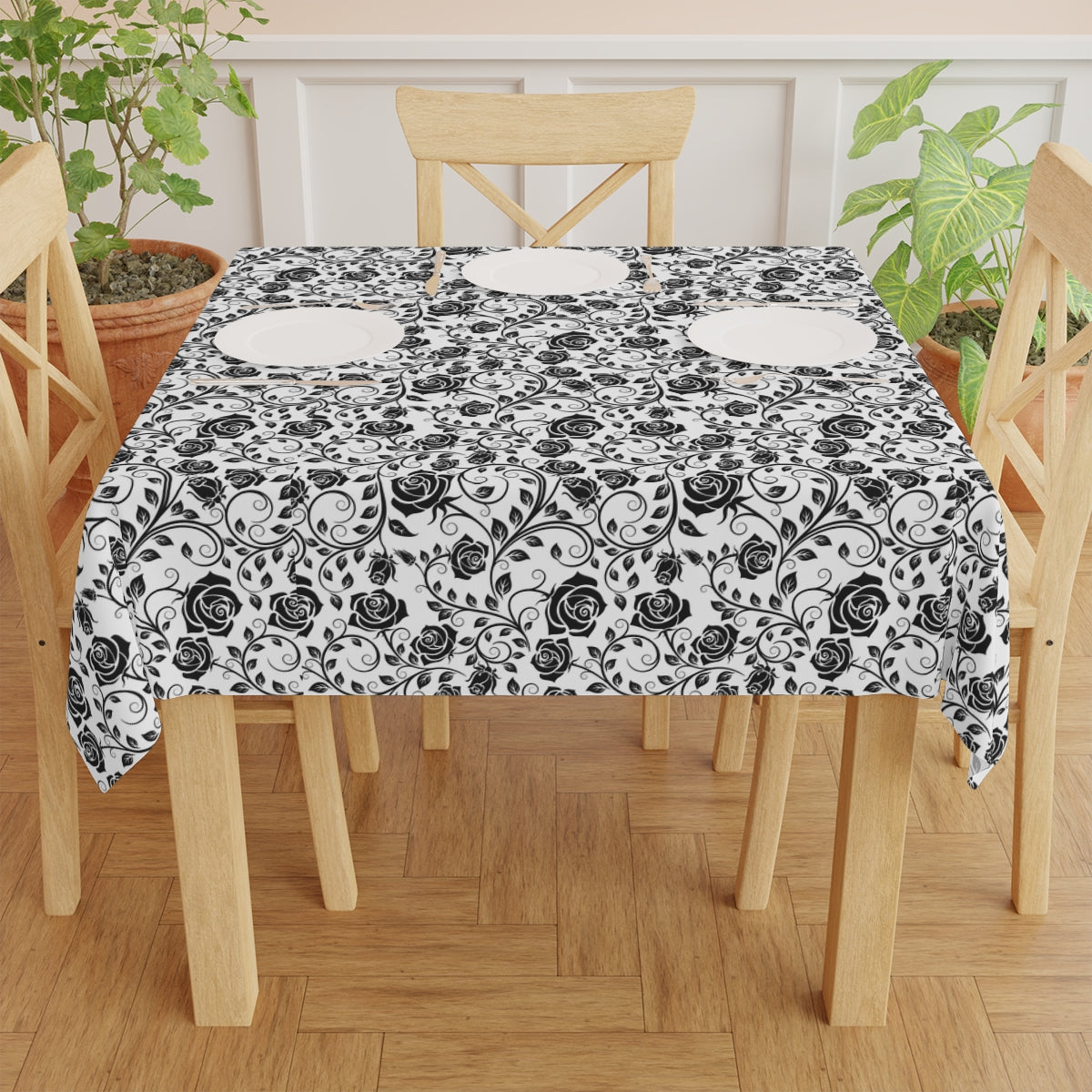 Dining table with a black and white floral patterned tablecloth on a wooden floor.