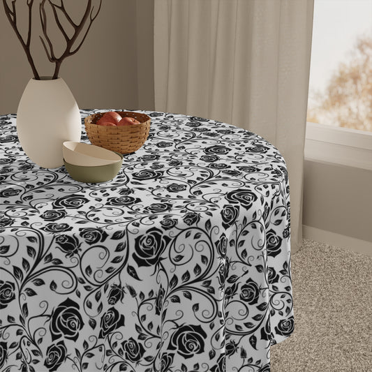 Round table with a black floral patterned tablecloth, accompanied by a woven basket and white bowl.