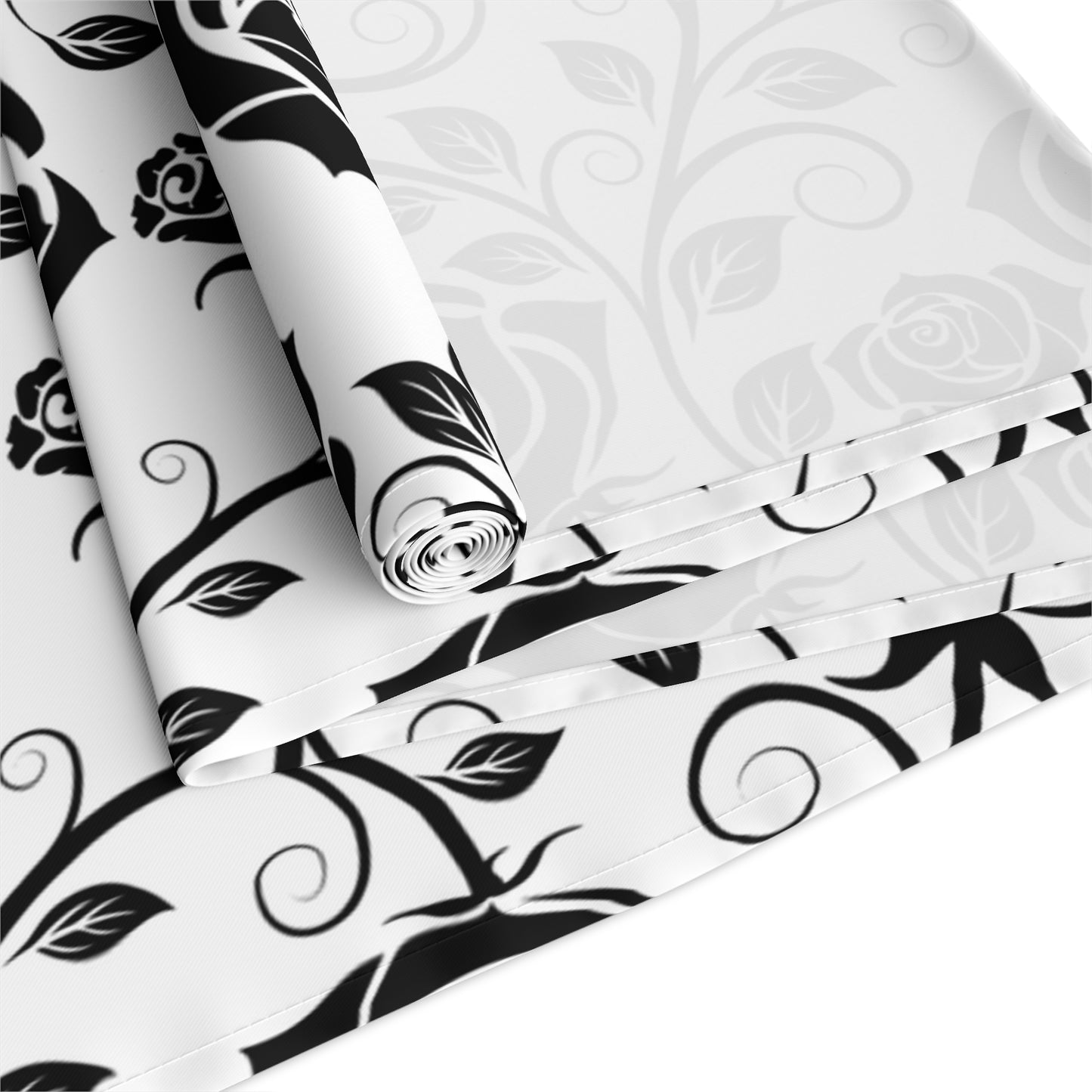 Black and white floral table runner rolled up and folded on a white background