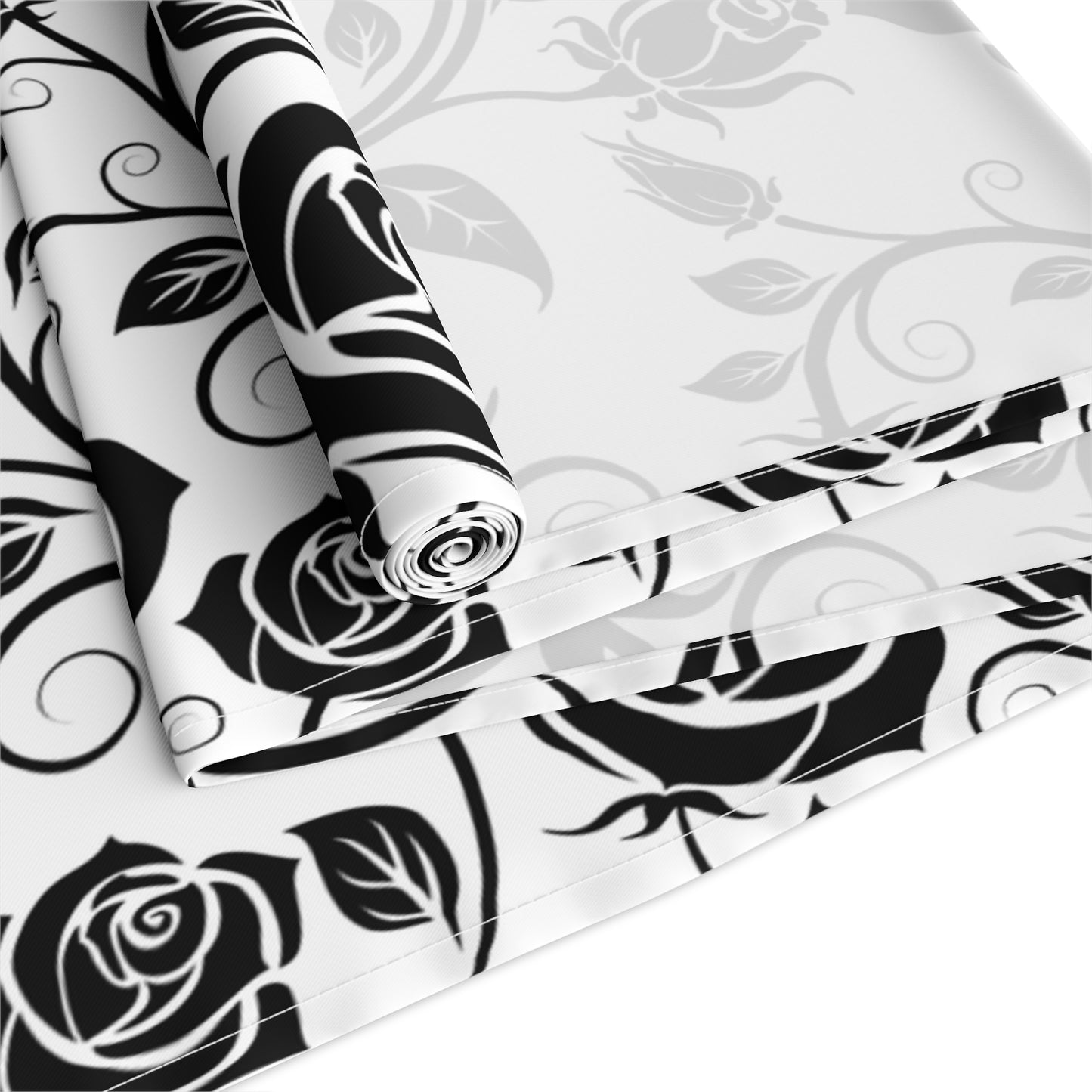Black floral pattern table runner rolled up and folded on a white background